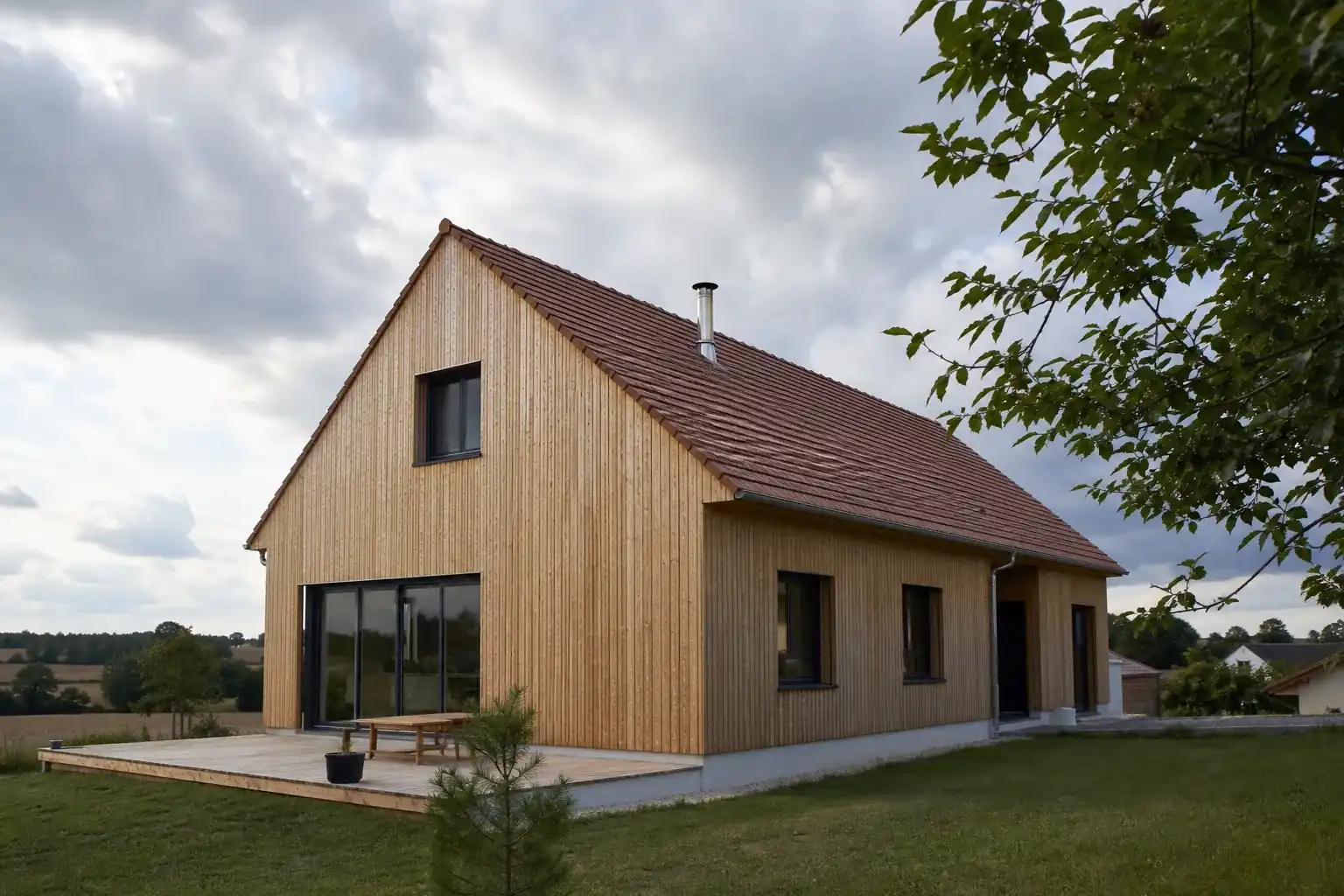 Maison en ossature bois avec bardage vertical clair et toiture à deux pans, vue de trois quarts